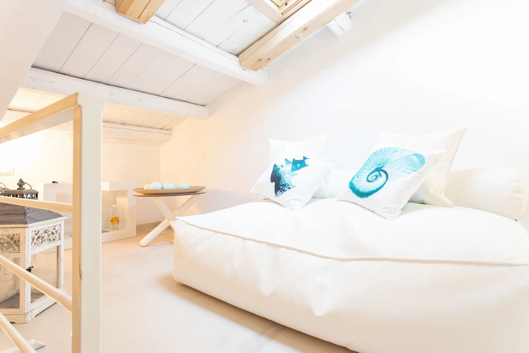 Un dormitorio luminoso con una cama baja y almohadas estampadas bajo un techo inclinado.