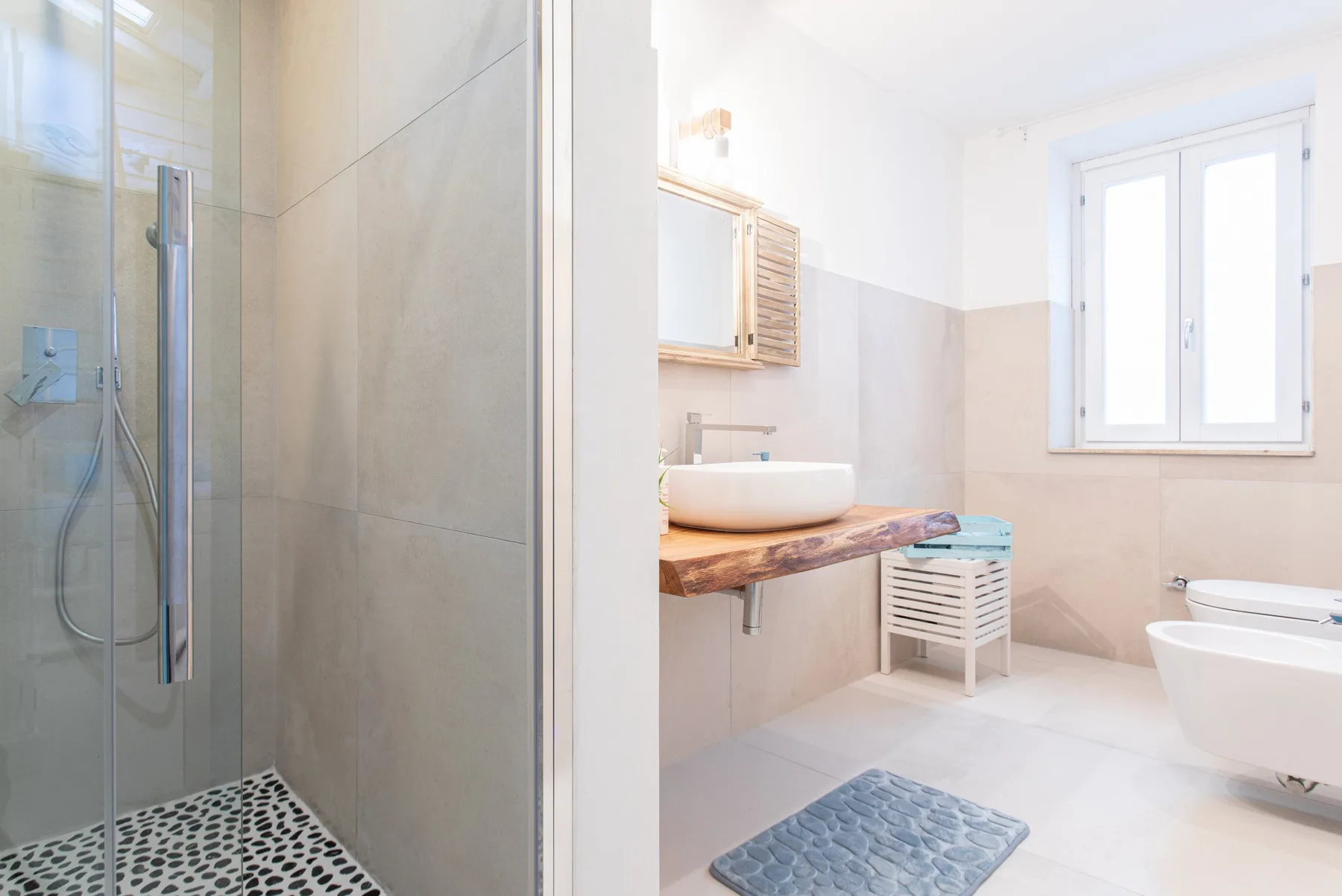 A bright bathroom with a glass shower, sink, and bathtub.