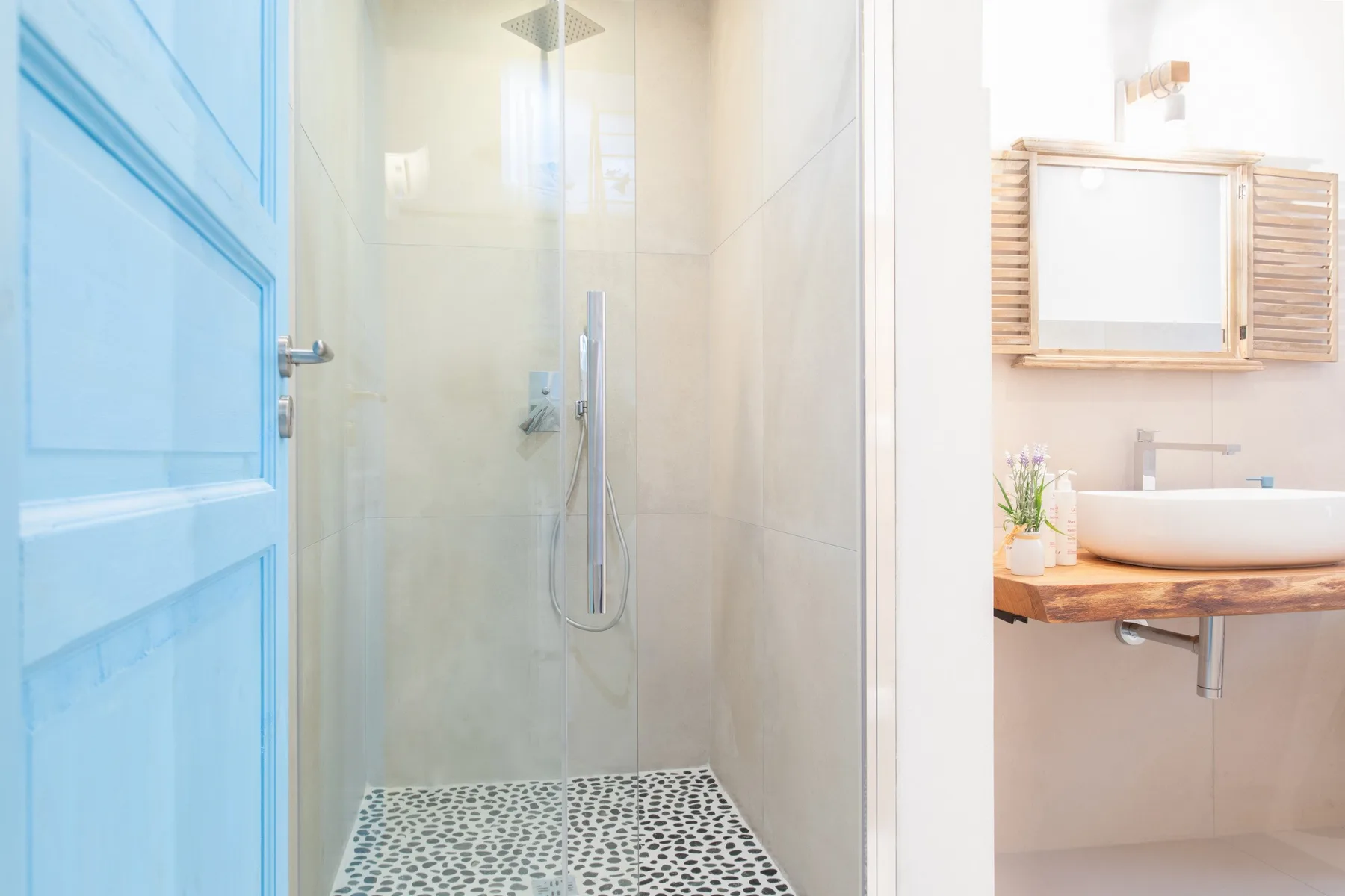 A bright bathroom with a glass shower and a wooden vanity.