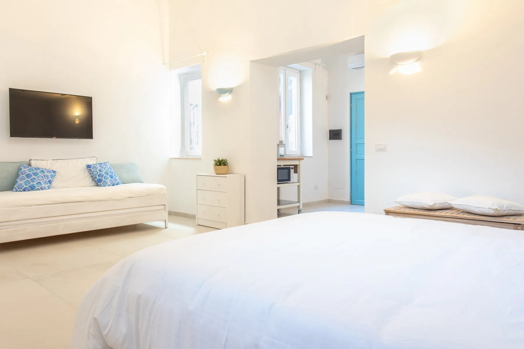 A bright bedroom with a large bed and a small seating area.
