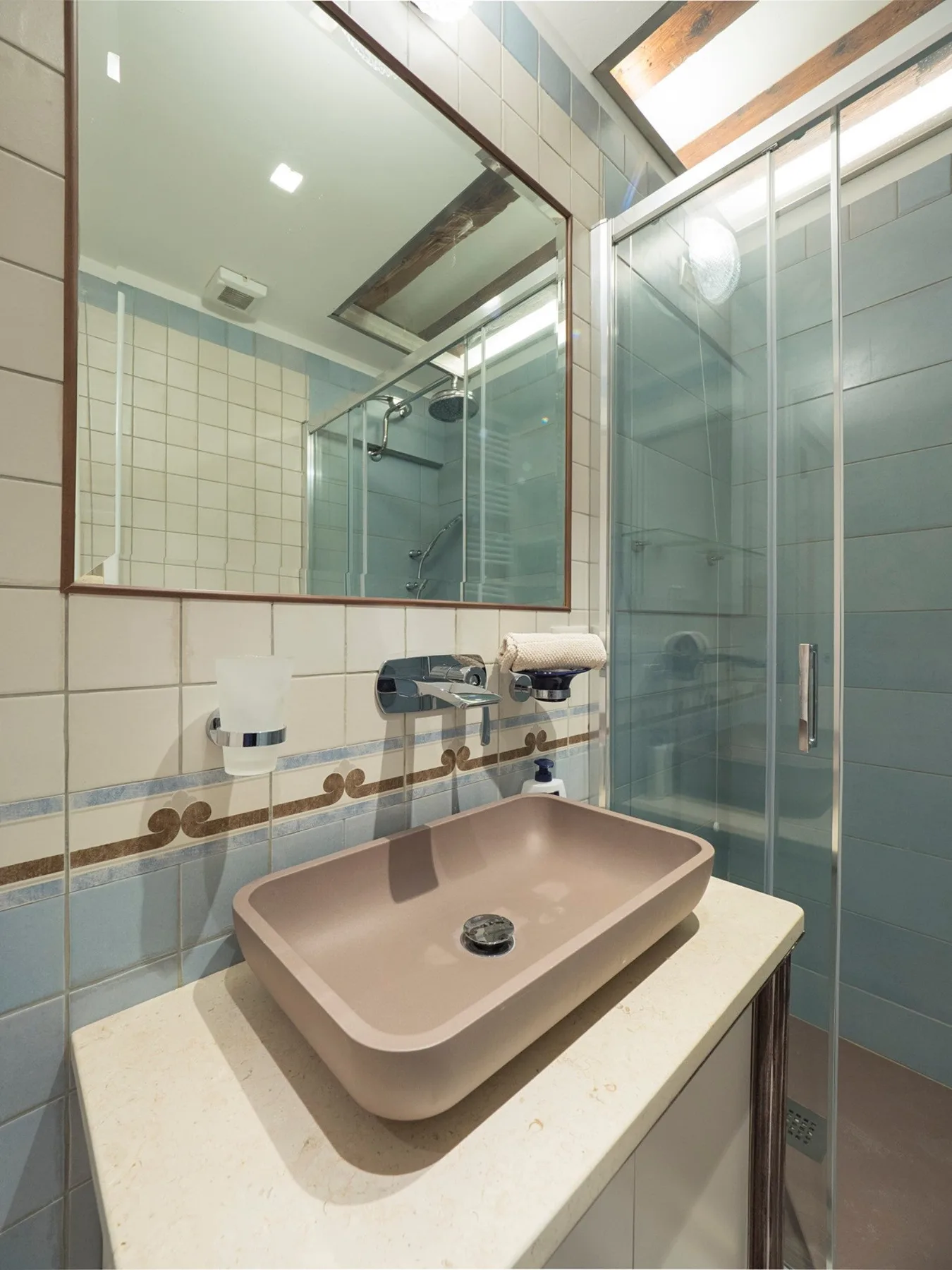 Un lavabo de baño con una poza sobrepuesta está junto a una ducha de vidrio.