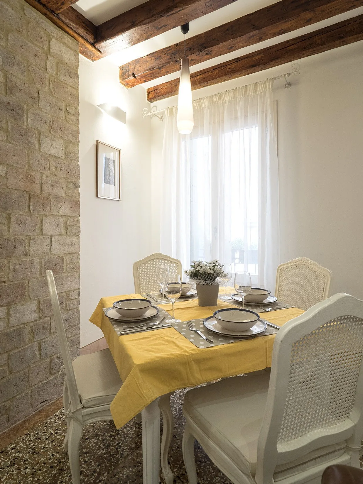 Un comedor con una mesa puesta bajo vigas de madera a la vista.
