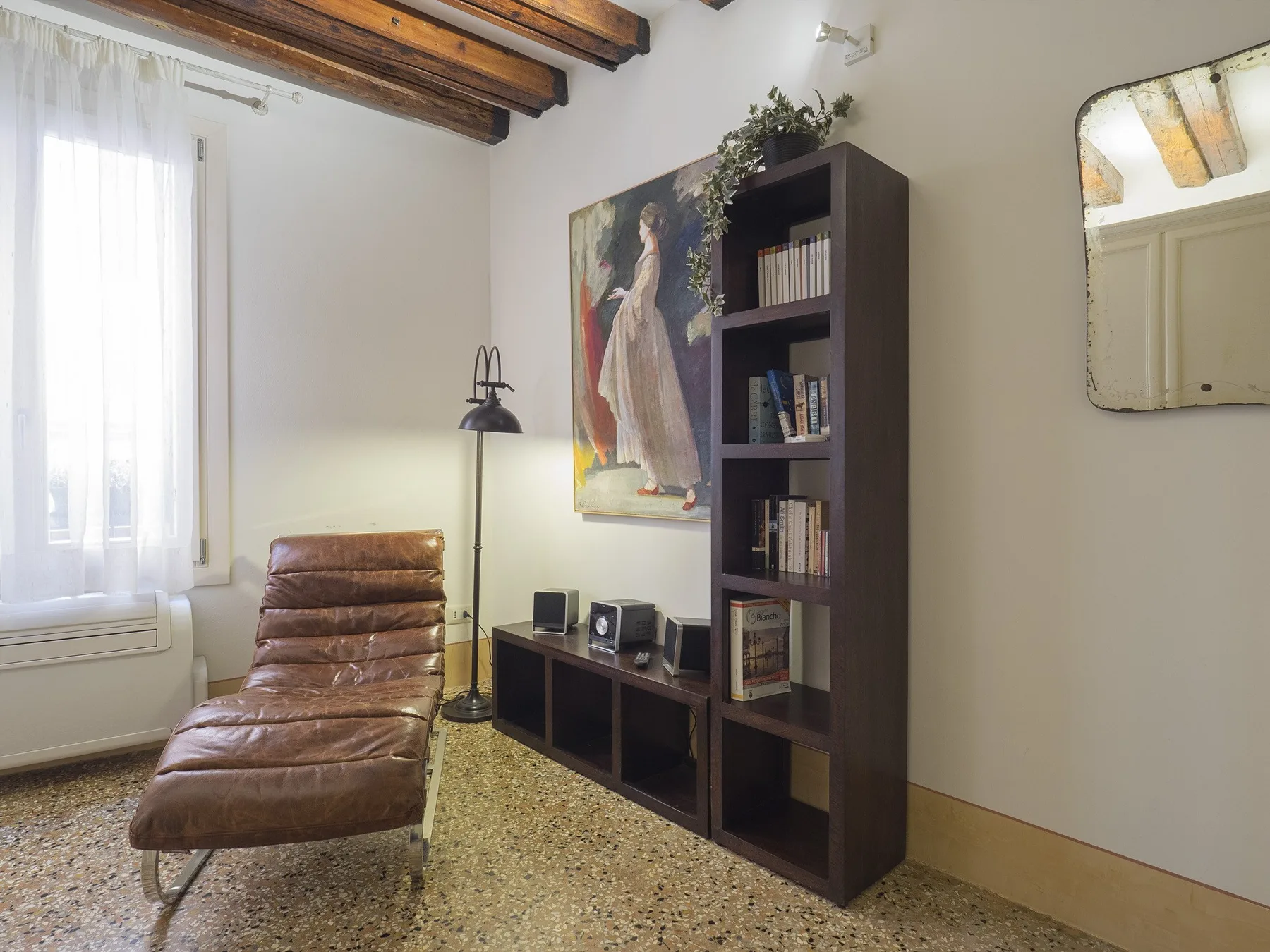 Una sala de estar con un sillón de cuero, una estantería y una obra de arte.