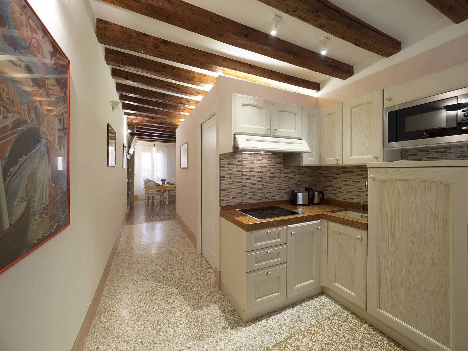 Una cocina compacta se abre a un pasillo con vigas de madera expuestas en el techo.