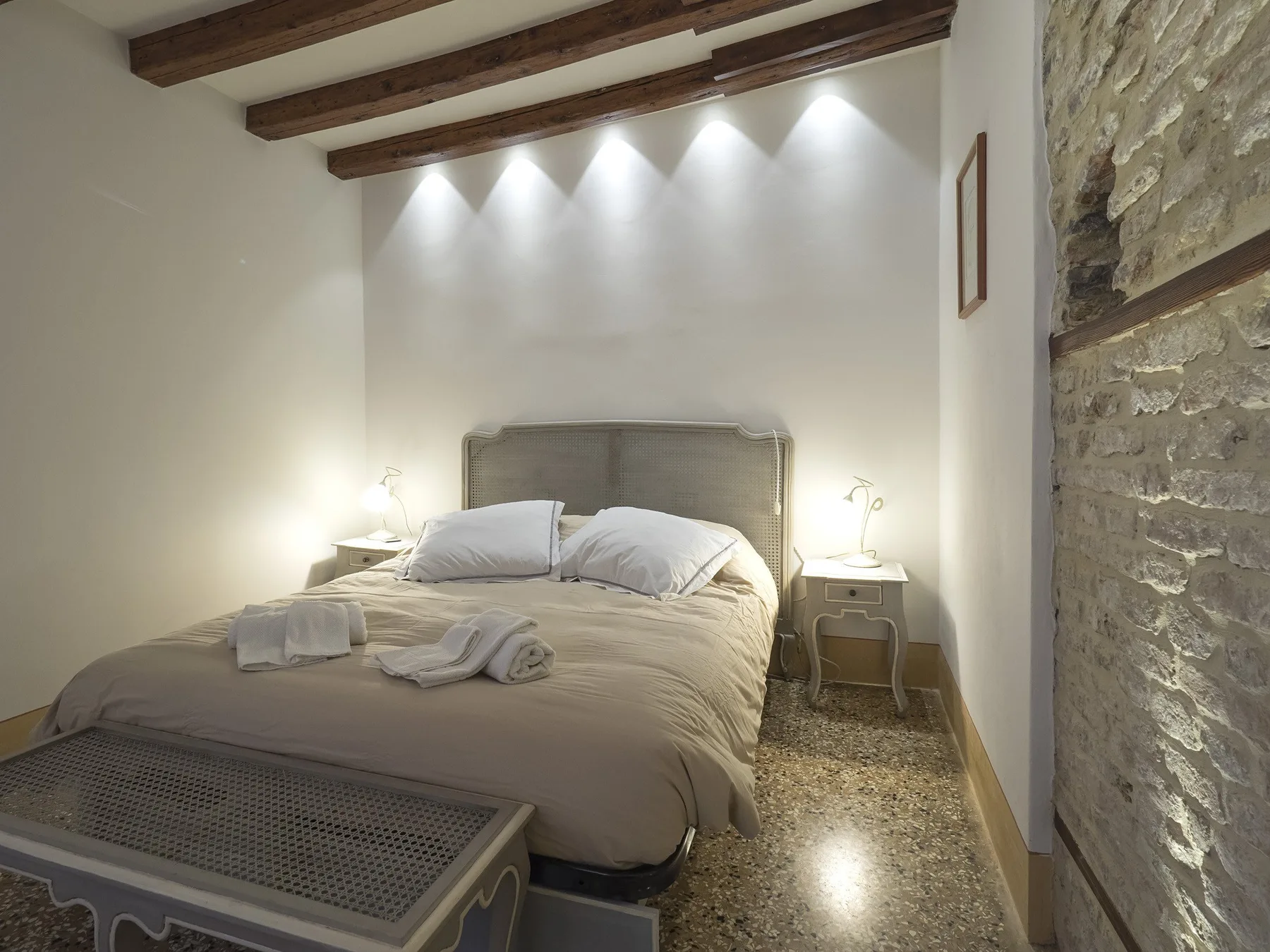 Un dormitorio con una cama bajo vigas de madera a la vista.
