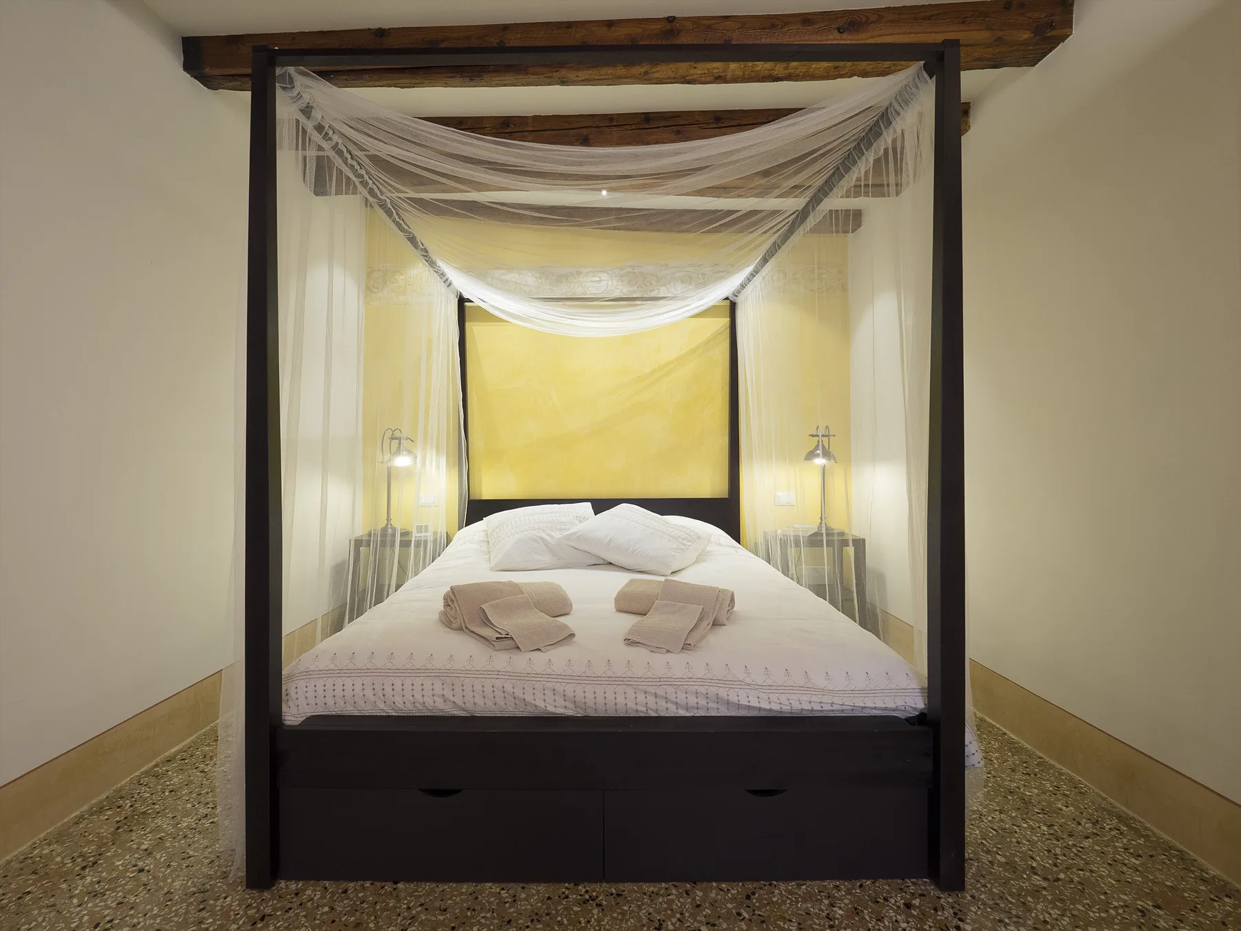 Un dormitorio con una cama con dosel y tela ligera suspendida encima.