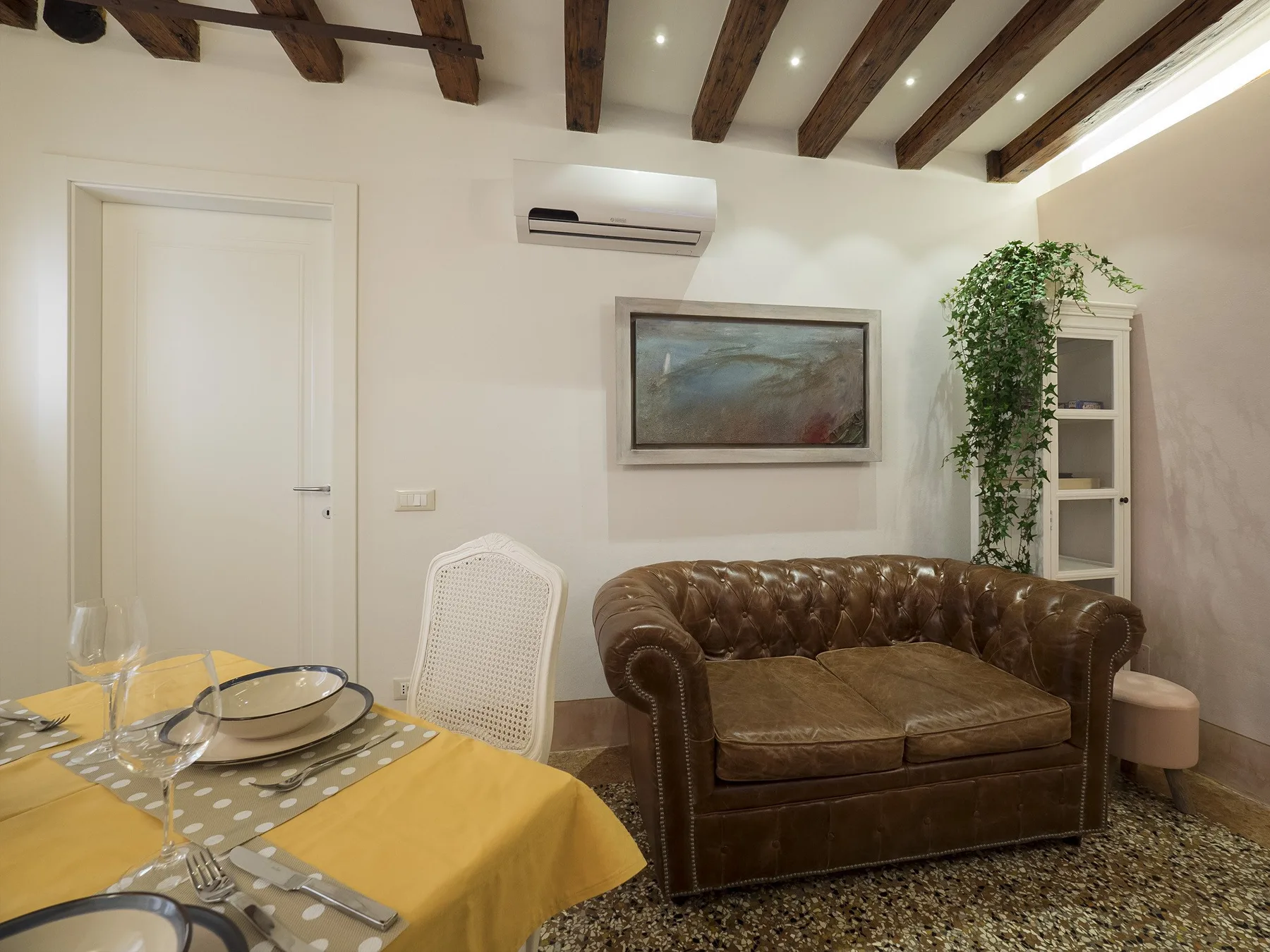 Una sala de estar y comedor con un sofá marrón y una mesa puesta.