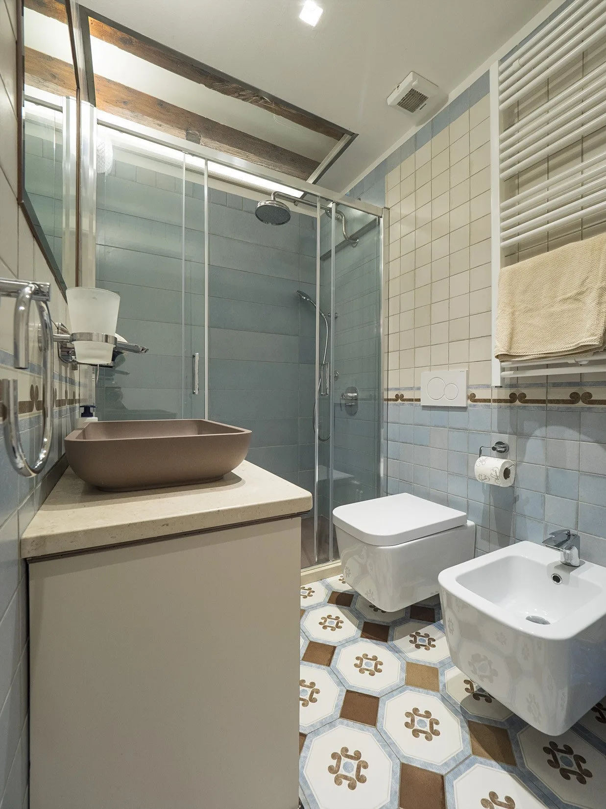 Un baño alicatado con ducha de vidrio, lavabo, inodoro y bidé.