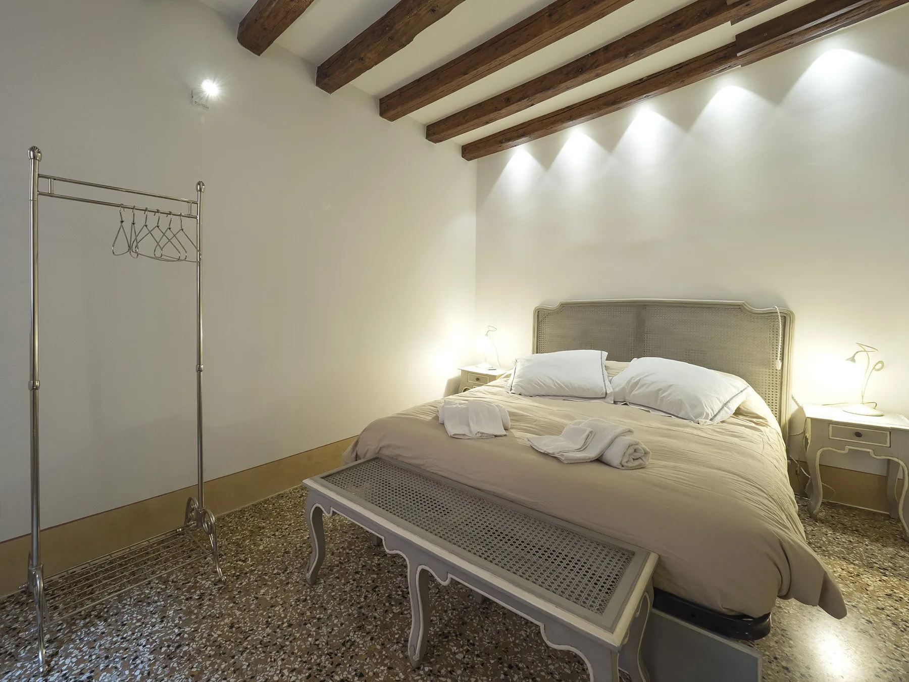 Un dormitorio con una cama grande y un banco a sus pies.