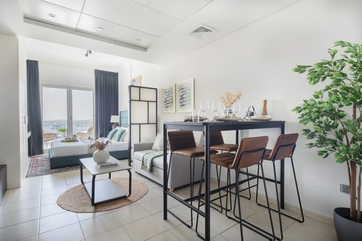 Una luminosa sala de estar y comedor diáfana, con una mesa y asientos junto a grandes ventanas.