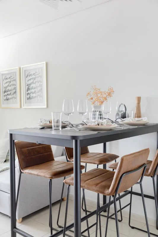 Un comedor con una mesa oscura, asientos marrones y cristalería.