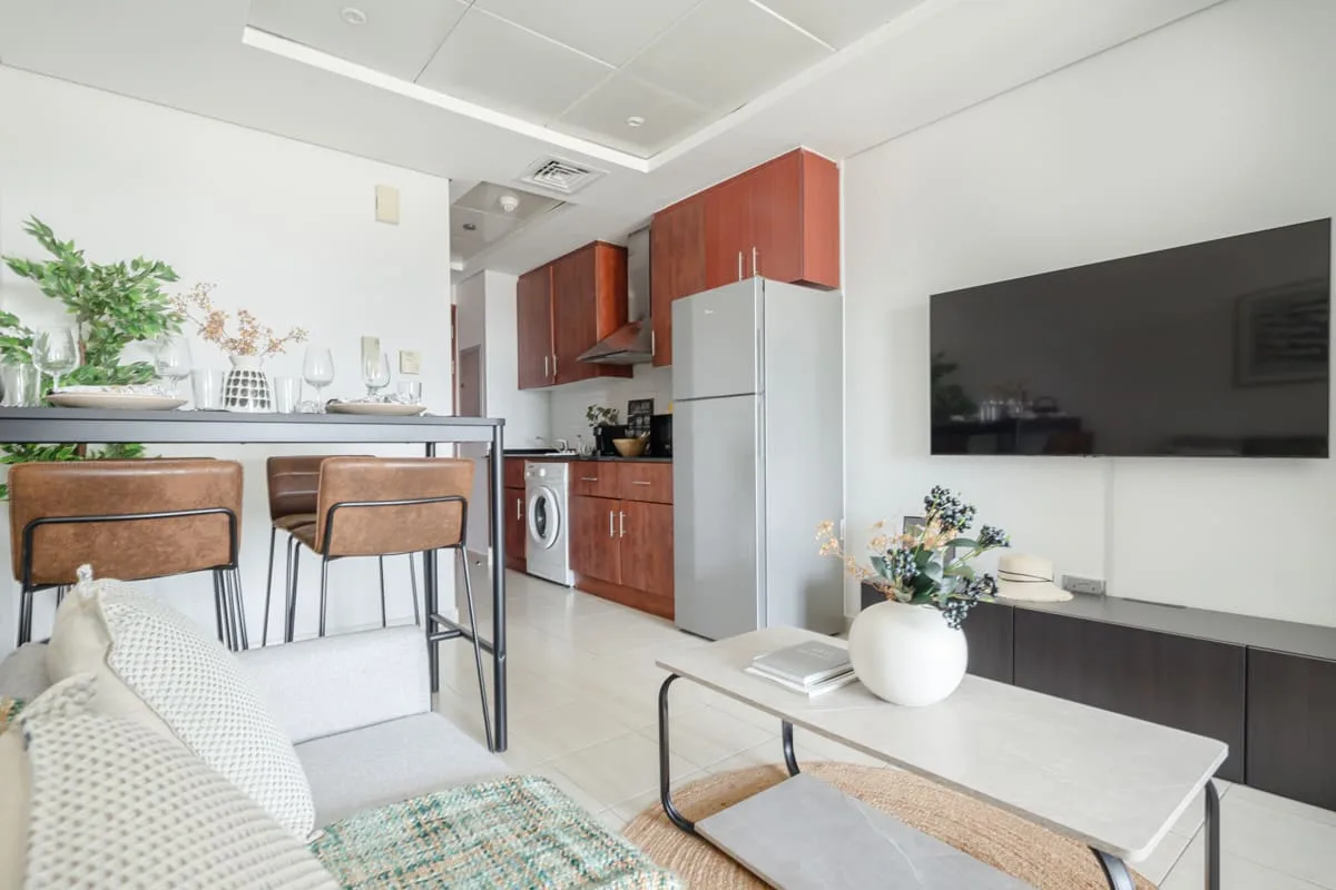 Una sala de estar y cocina de concepto abierto con una barra de comedor y televisor en la pared.