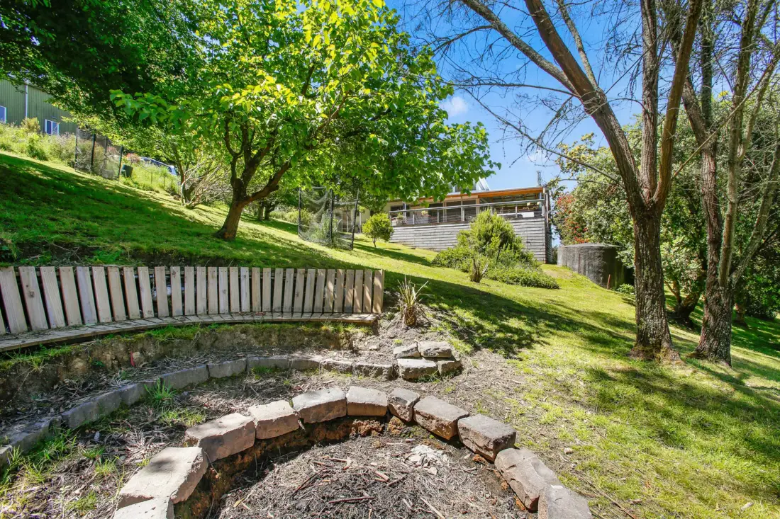 A landscaped garden with a curved stone-edged planting bed and trees.