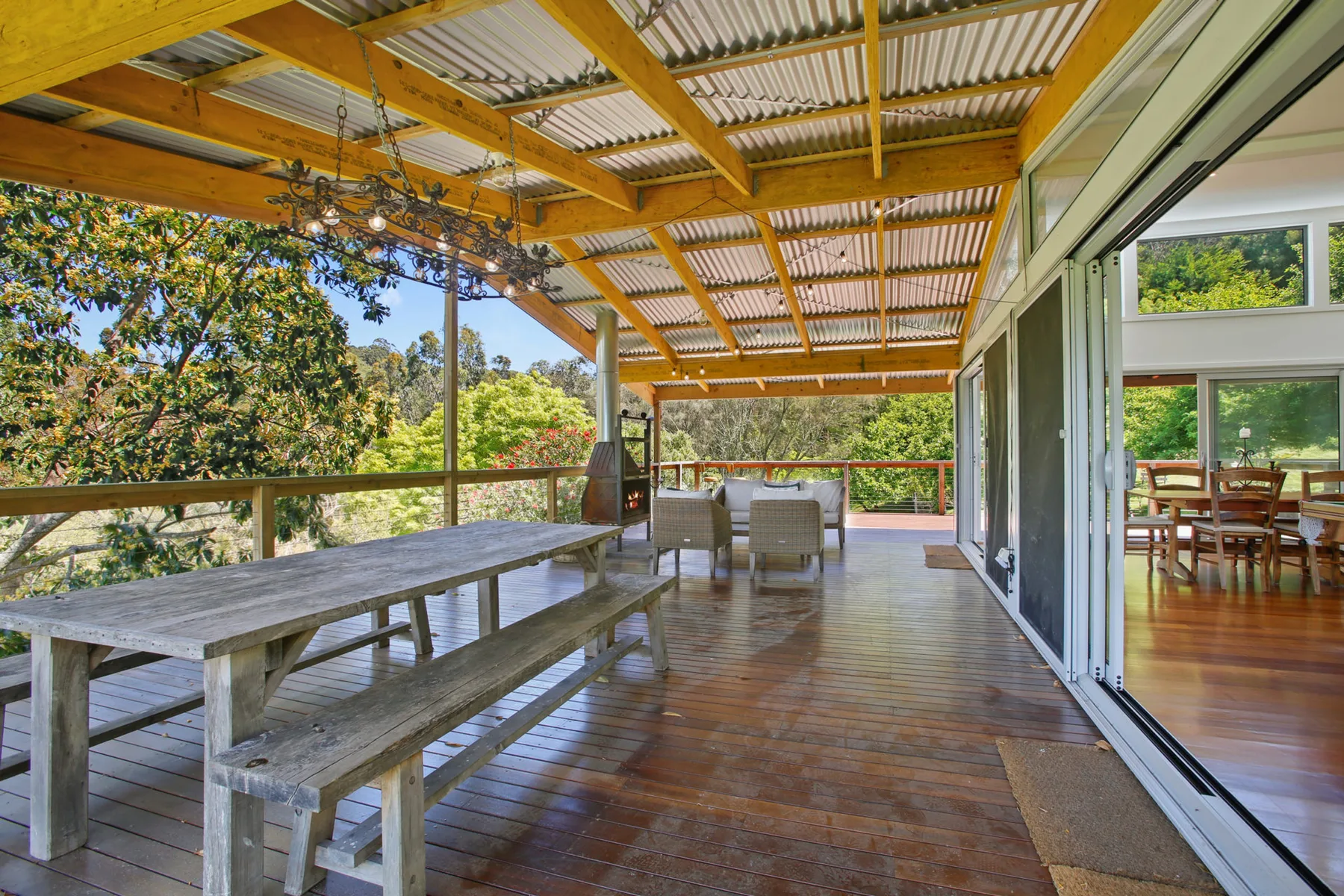 A covered wooden deck with outdoor seating and leafy views.