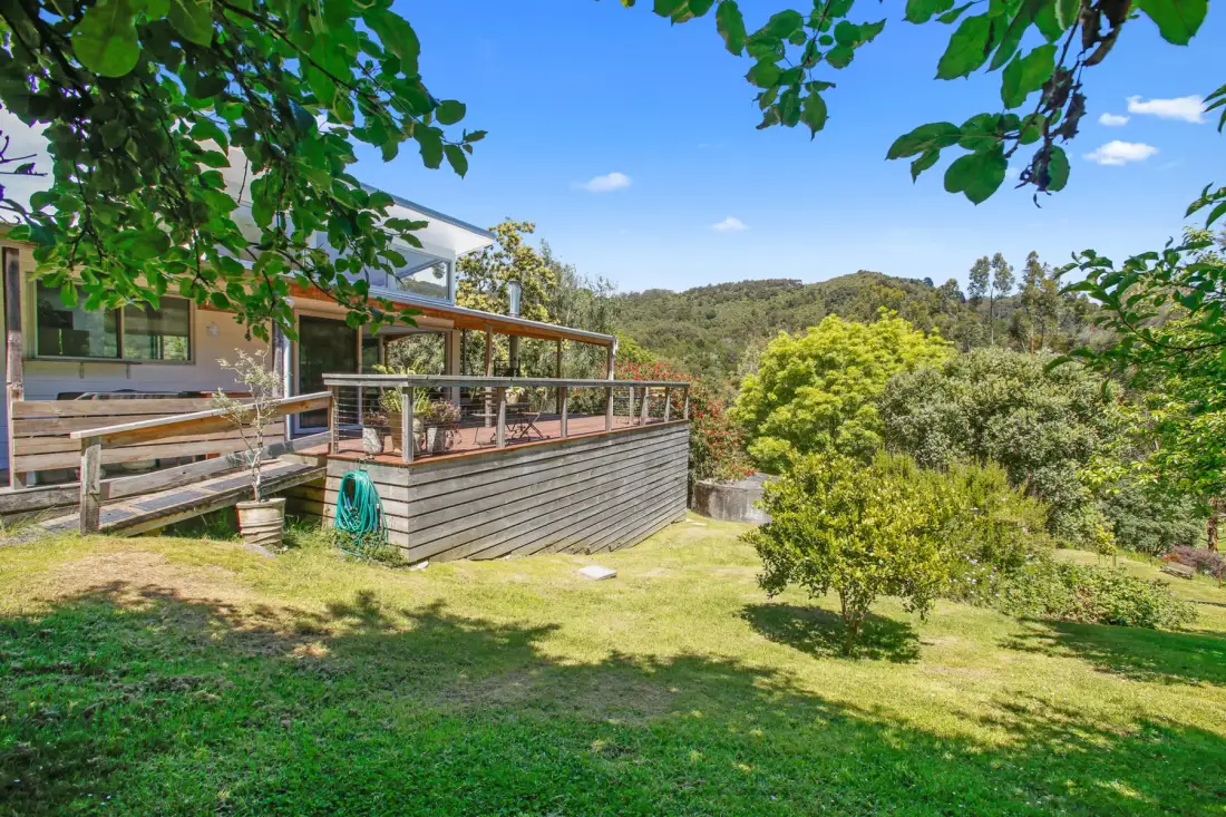 A house and raised deck overlook a green, tree-covered hillside.