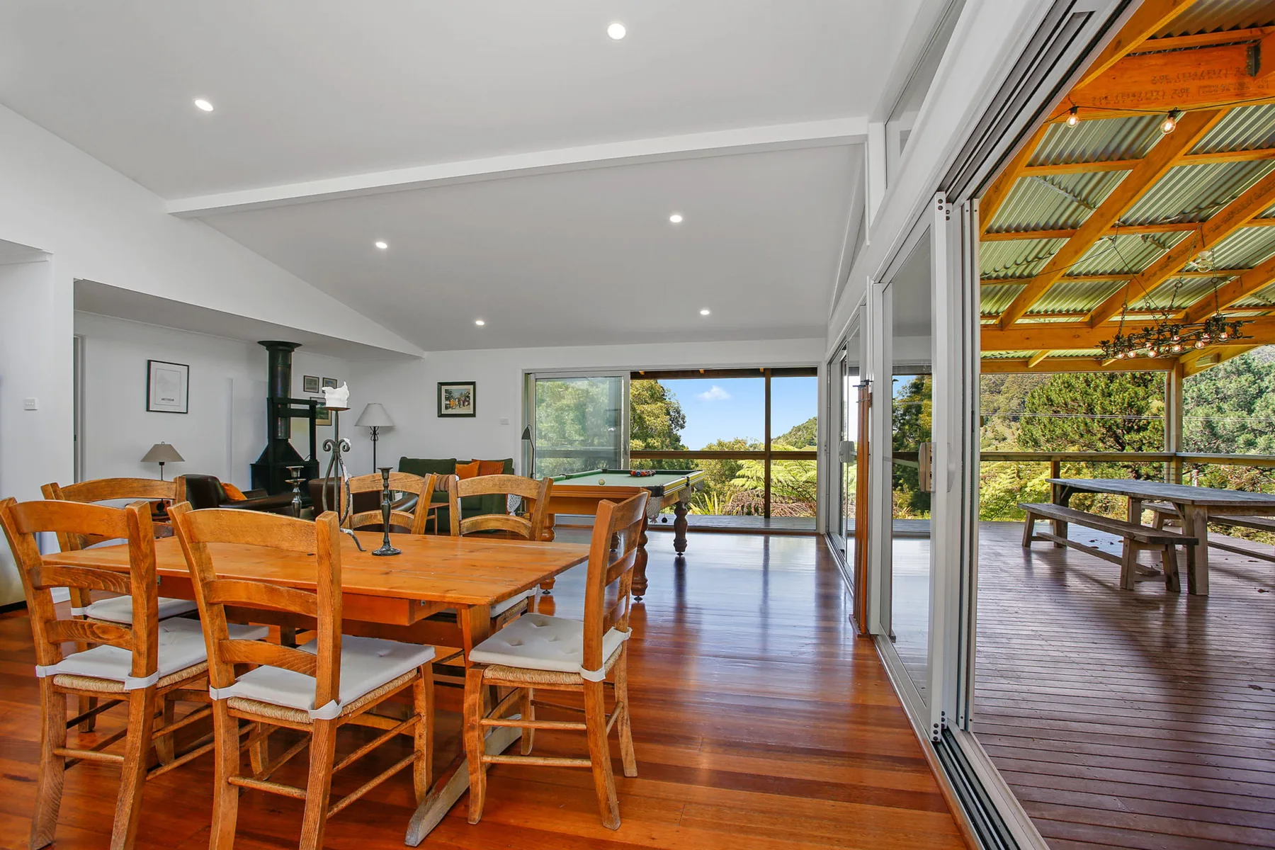 A dining area opens onto a covered deck through wide glass doors.