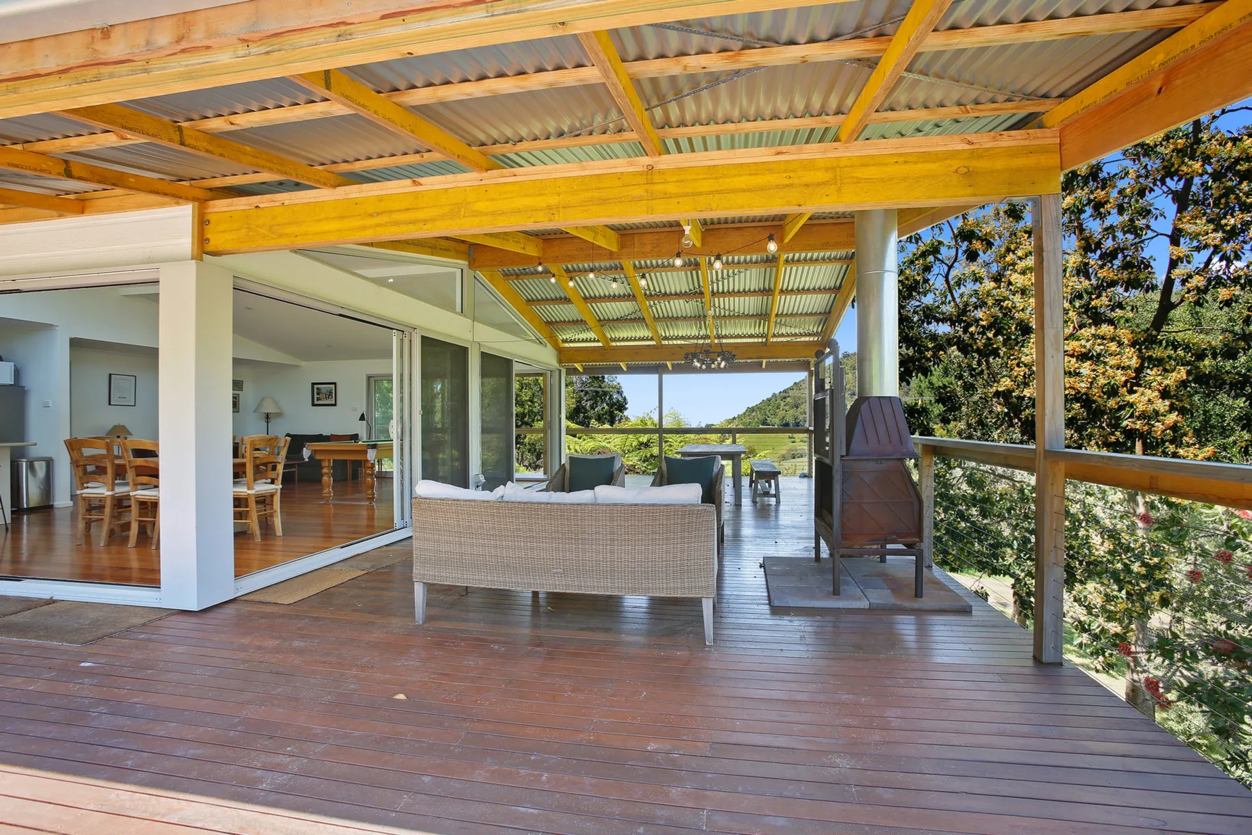 A covered outdoor deck with seating and an open view toward trees.