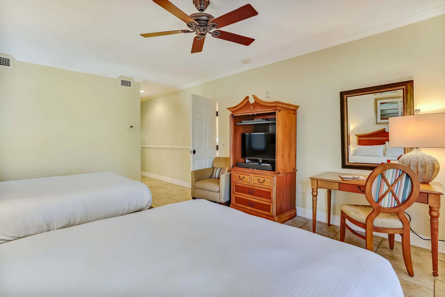A bedroom with two beds, a television cabinet, and a small table.
