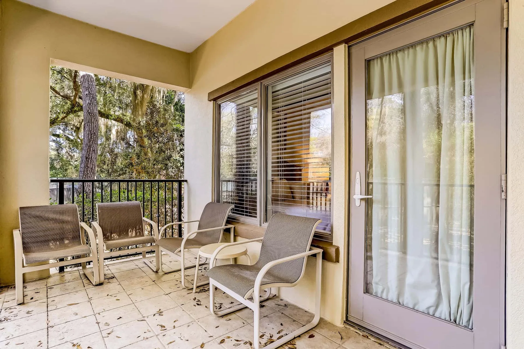 A tiled balcony with seating and sliding glass doors.