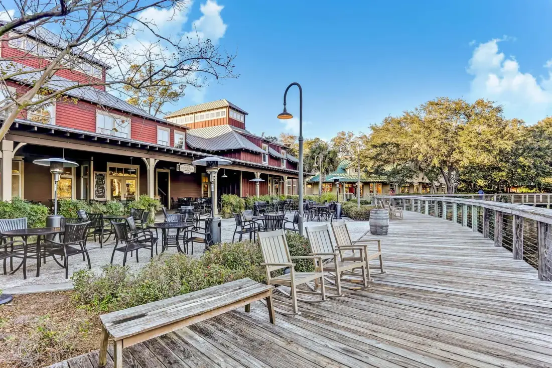 An outdoor dining area beside a wooden boardwalk, with tables and seating.