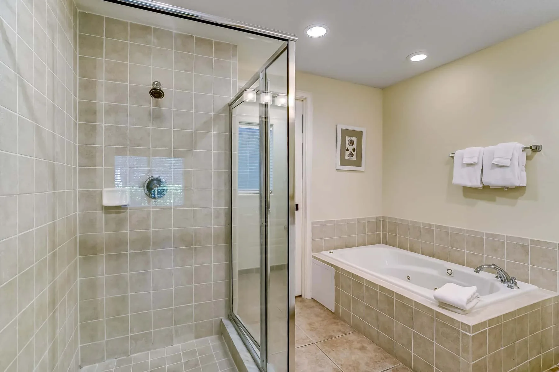 A tiled bathroom with a glass shower and a built-in bathtub.
