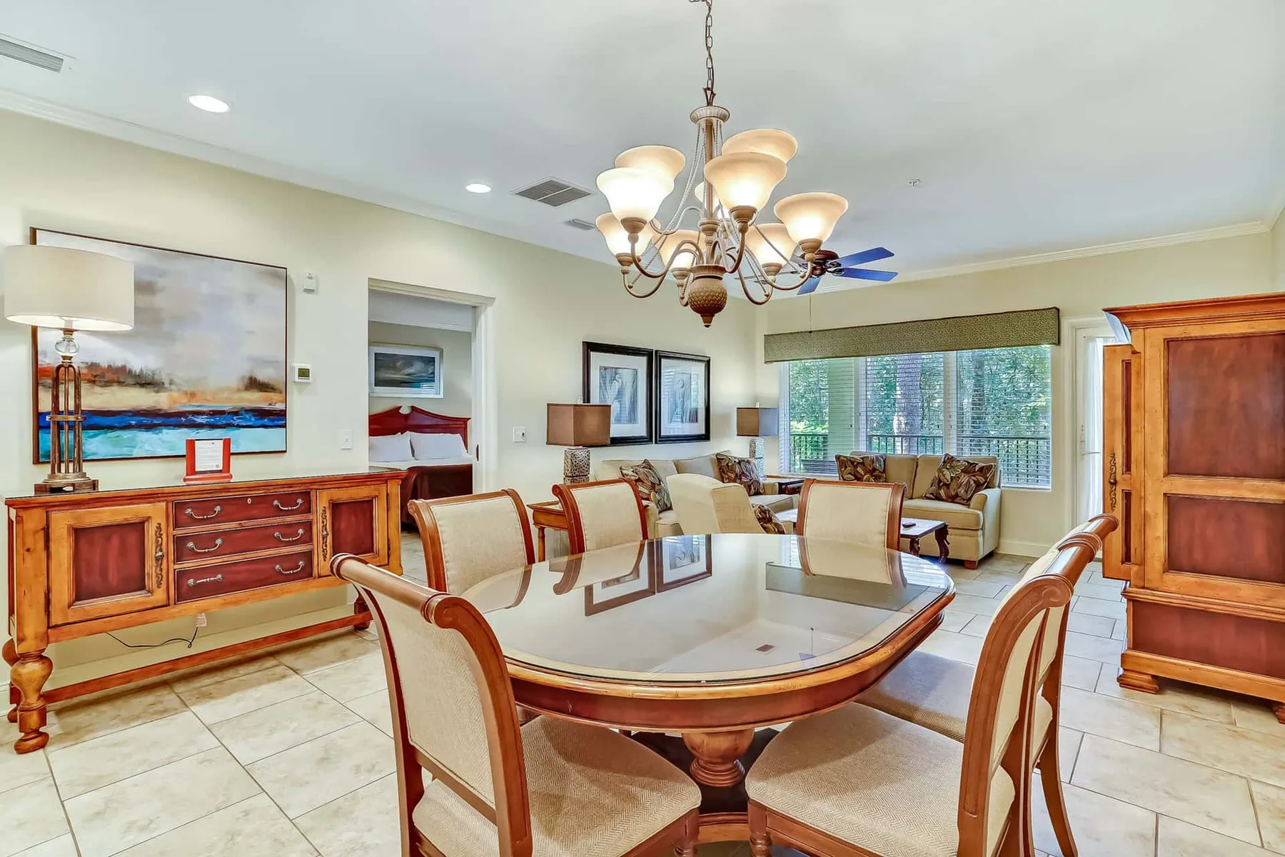 A dining room with a large table and chairs beneath a chandelier.