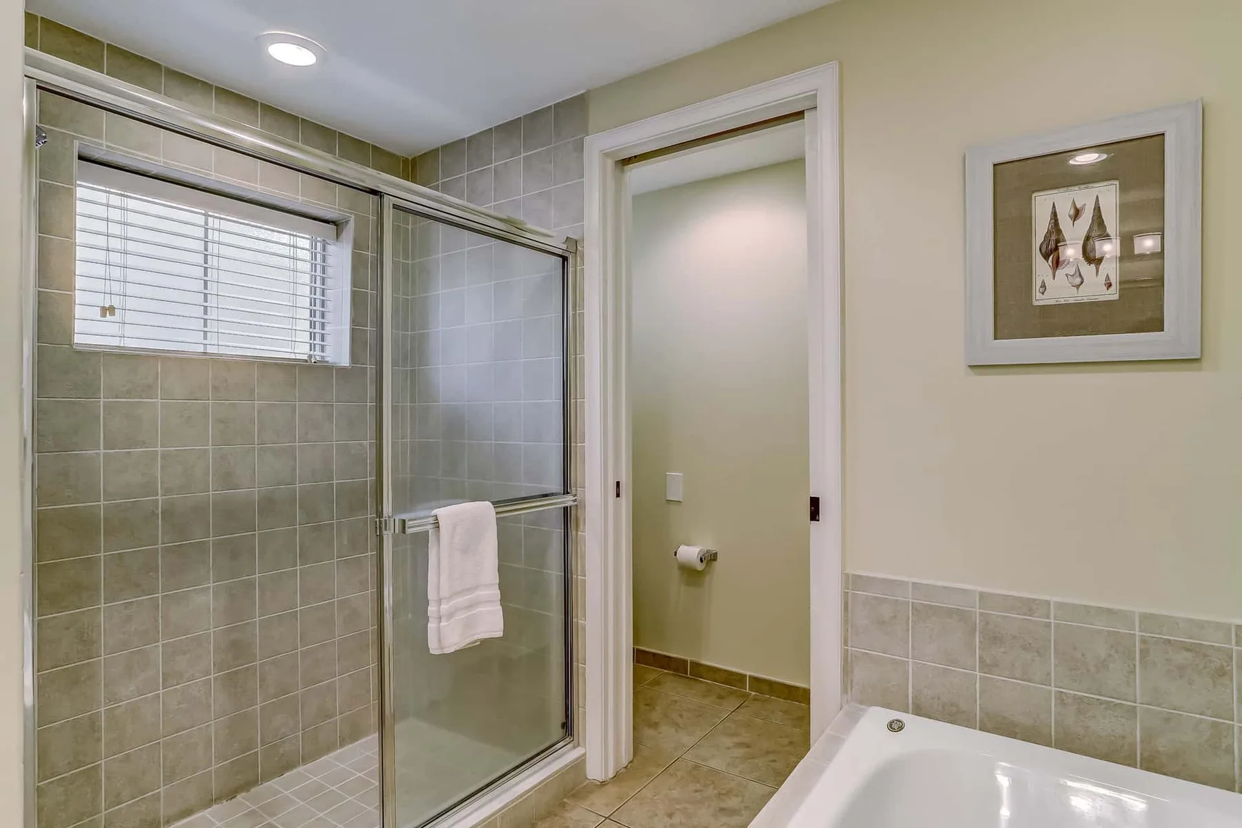 A tiled bathroom with a glass shower and a bathtub.