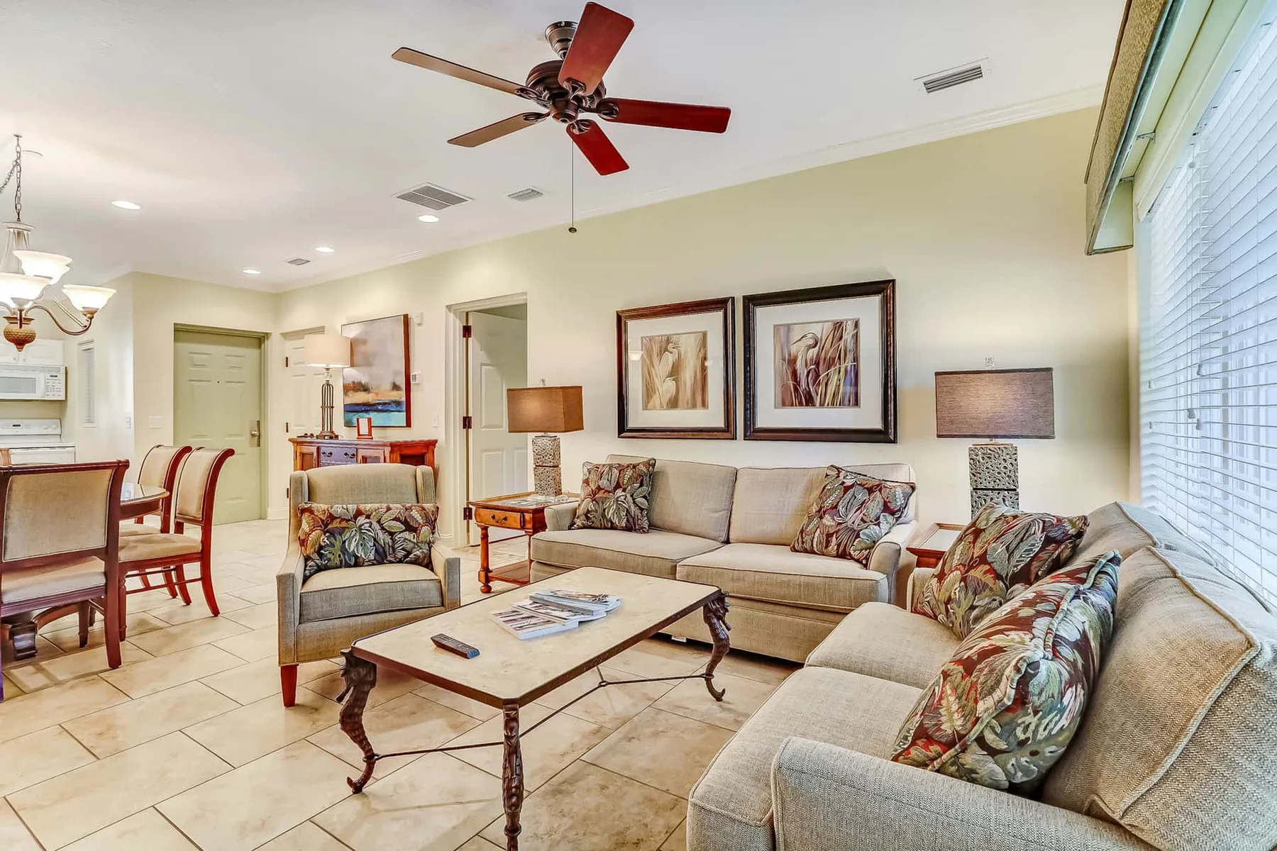 A living room with seating around a coffee table and a ceiling fan.