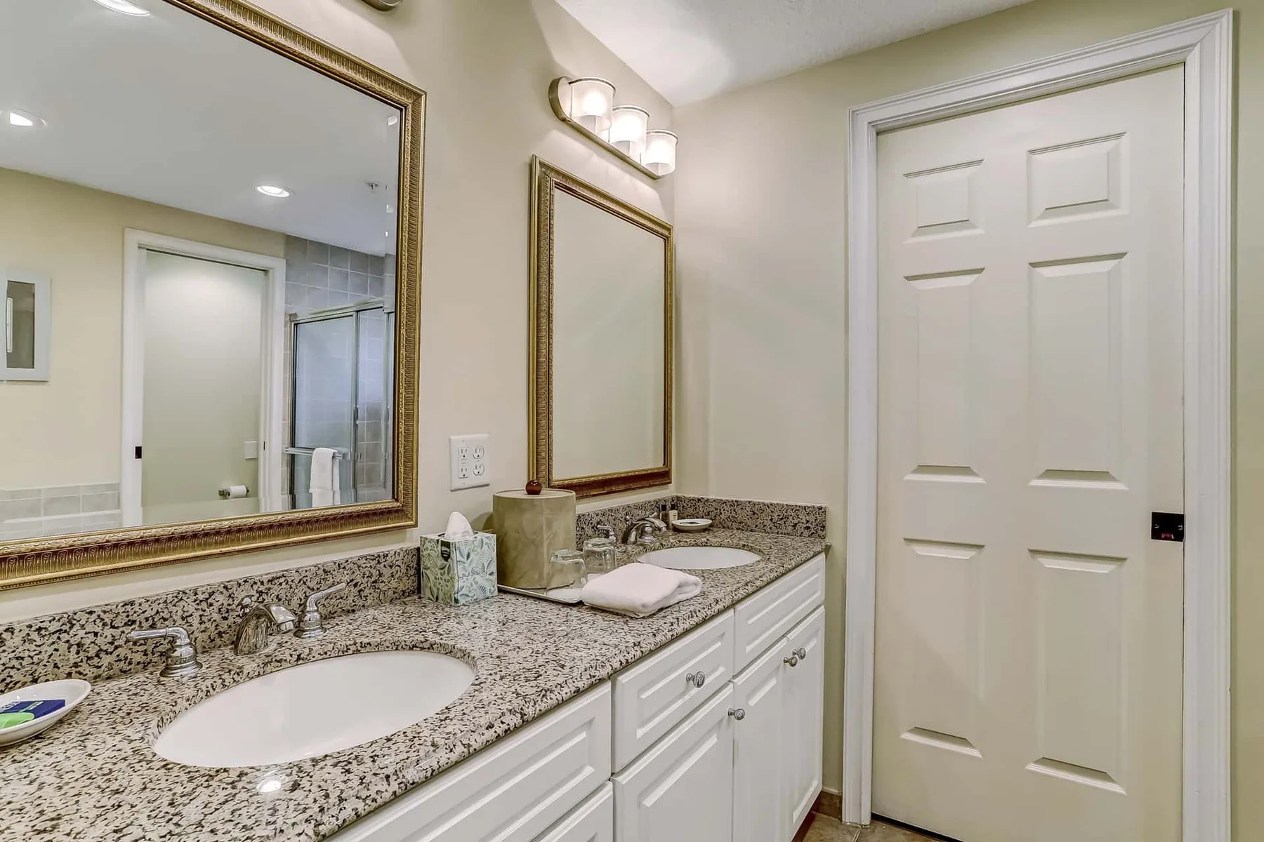 A bathroom vanity with a speckled countertop, sink, and large mirror.