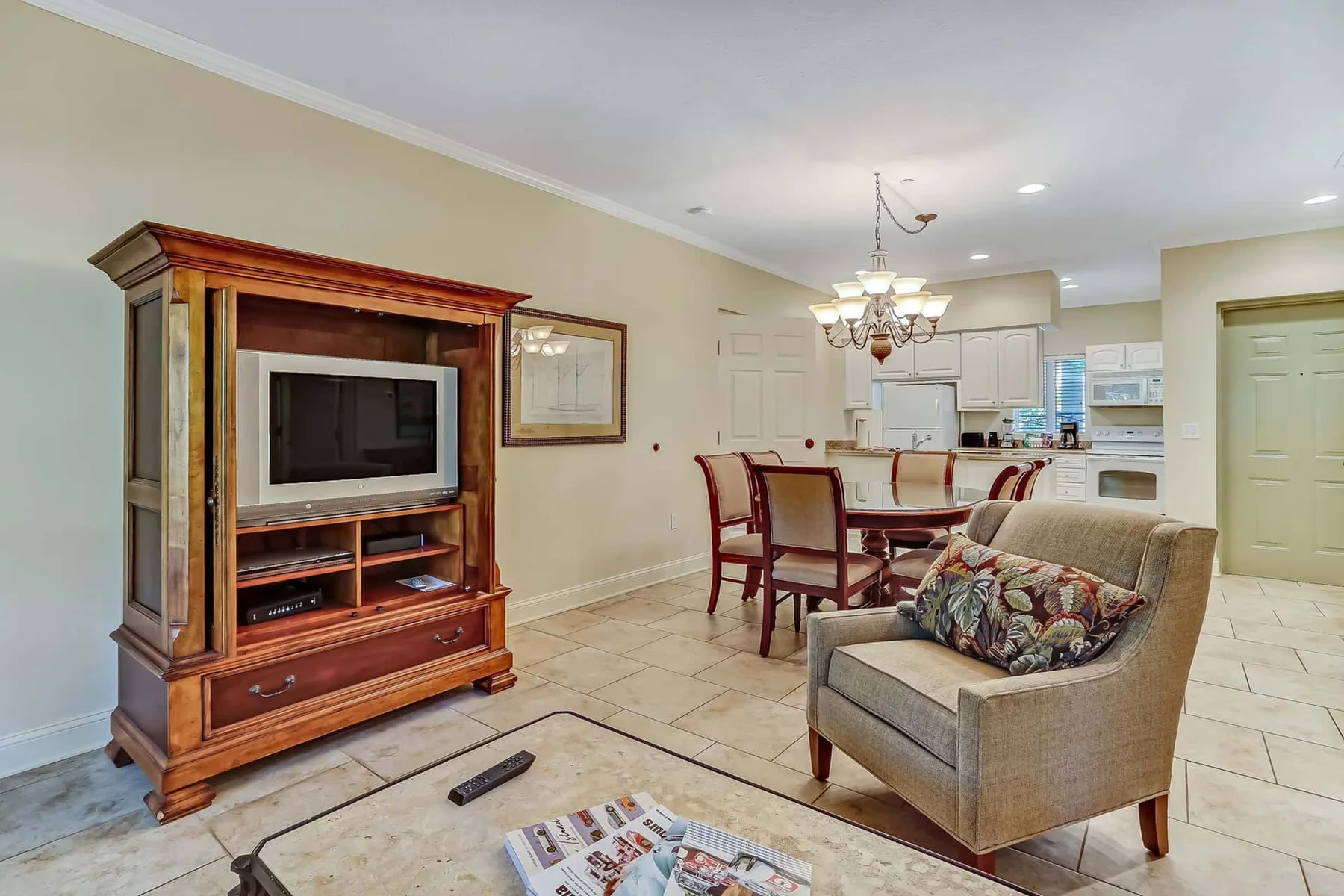 A living and dining area with a television cabinet, seating, and an open kitchen.