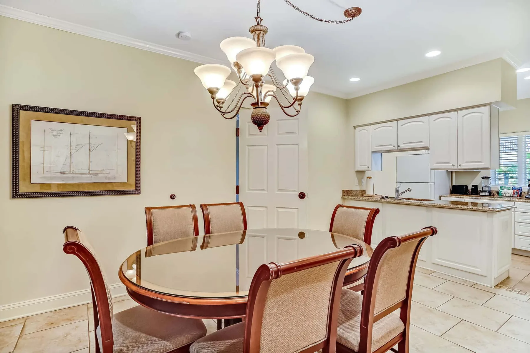 A dining area with a round table and chairs beside a kitchen.