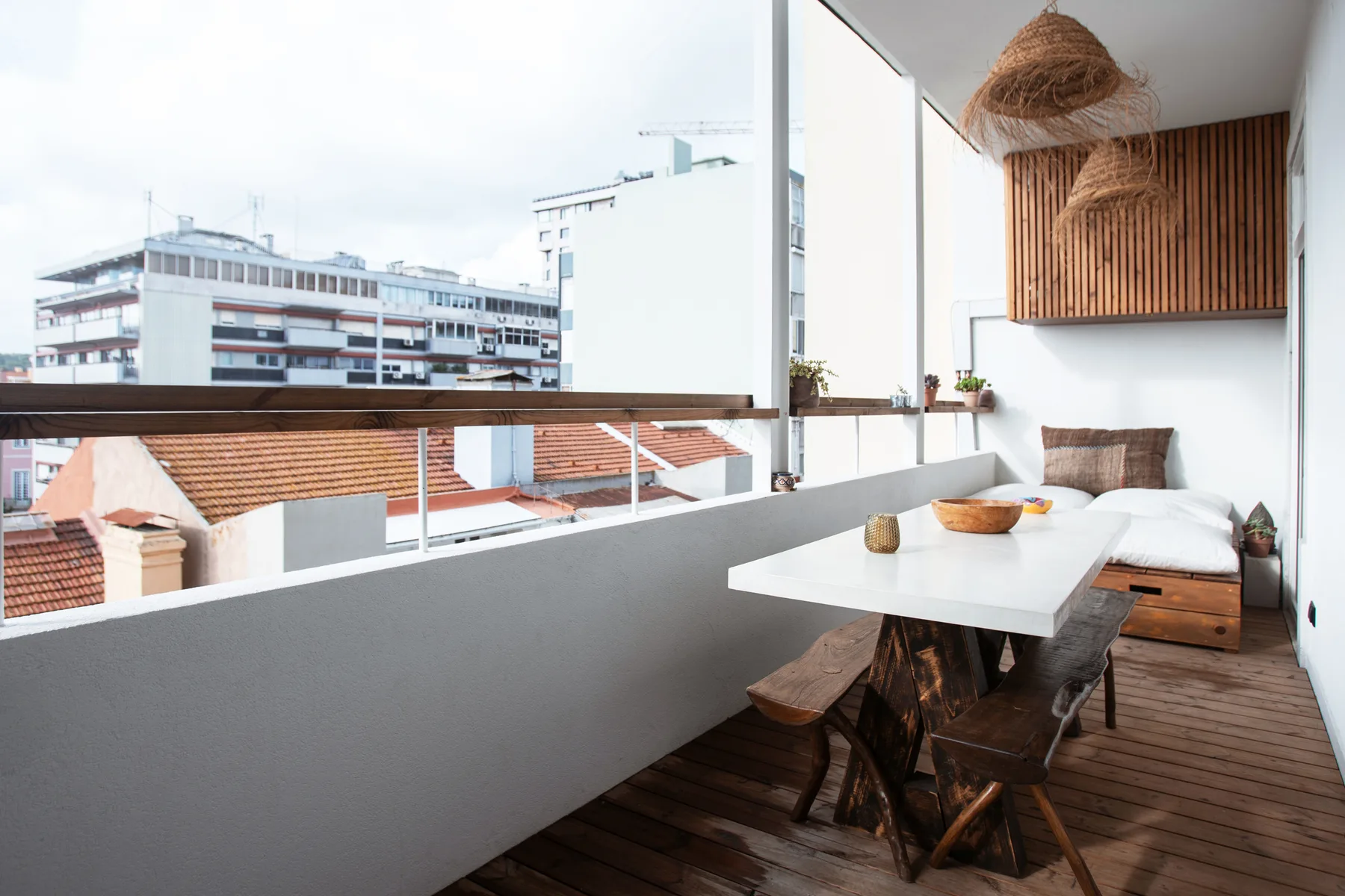 A balcony seating area with a white table and views of nearby buildings.