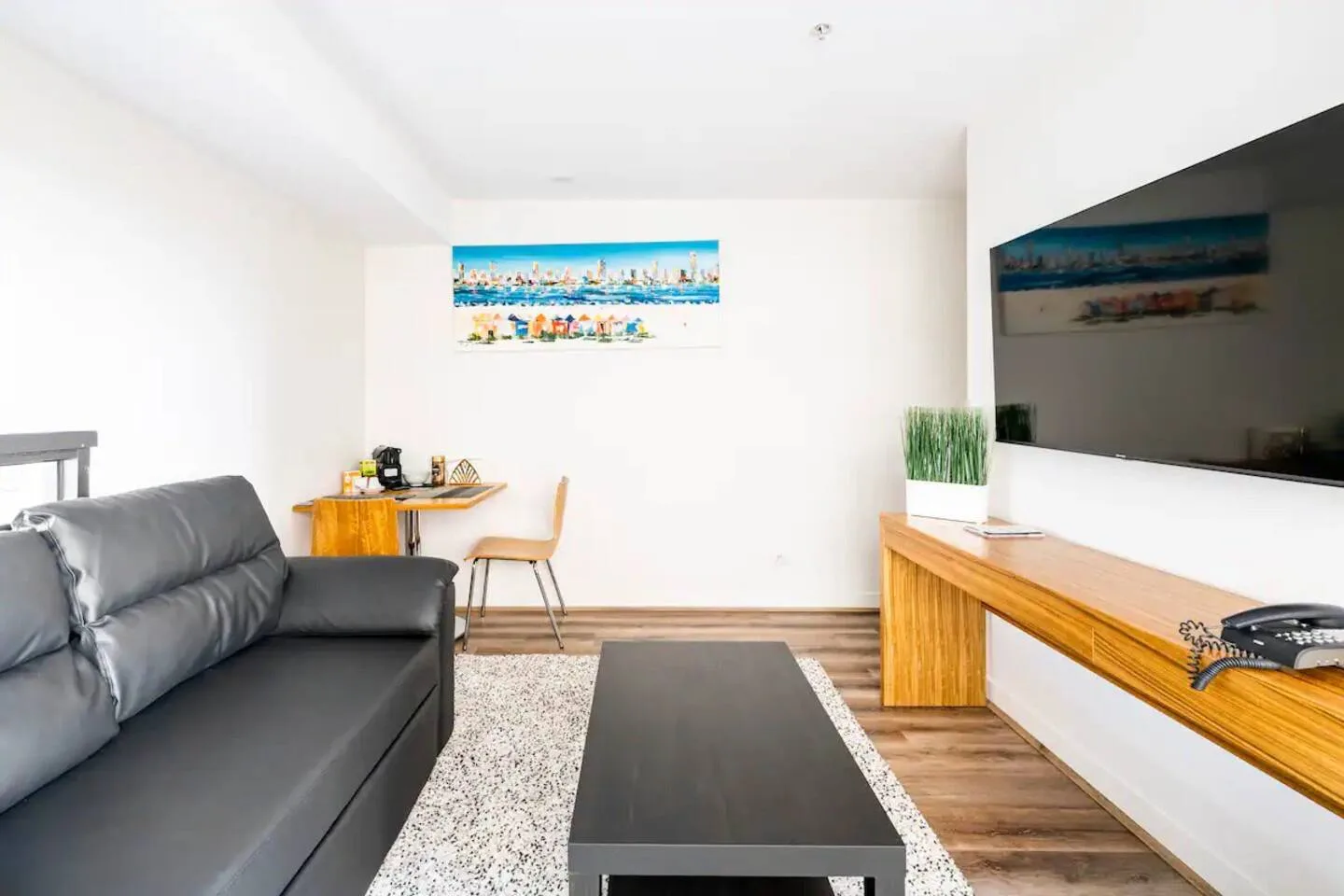 A living room with a dark sofa, coffee table, and wall-mounted television.
