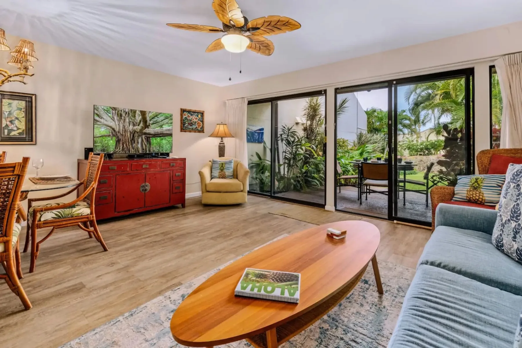 Una sala de estar con asientos, una mesa de centro y puertas de vidrio que dan a un jardín.