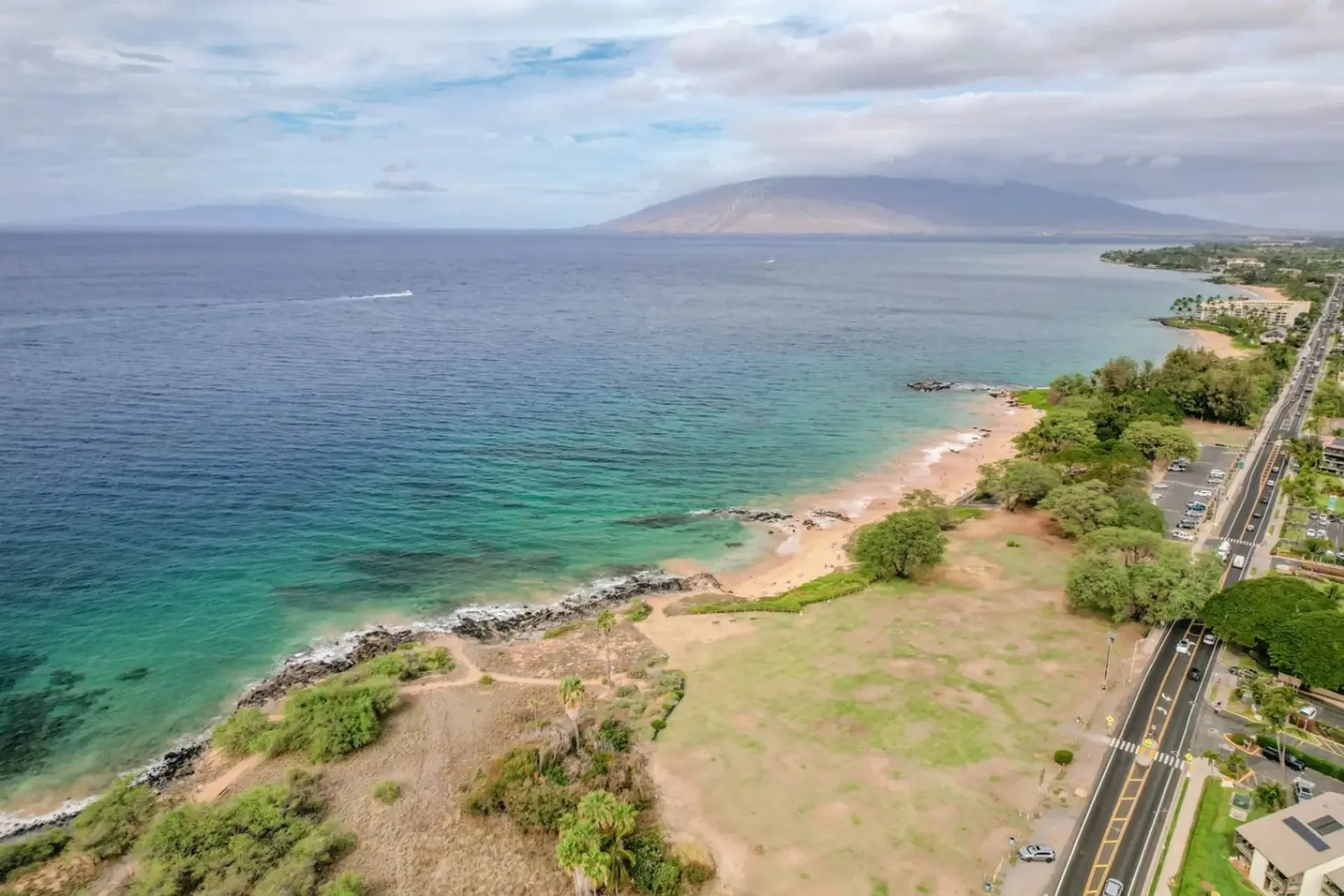 Vista aérea de una costa turquesa, con una playa de arena junto a una carretera.