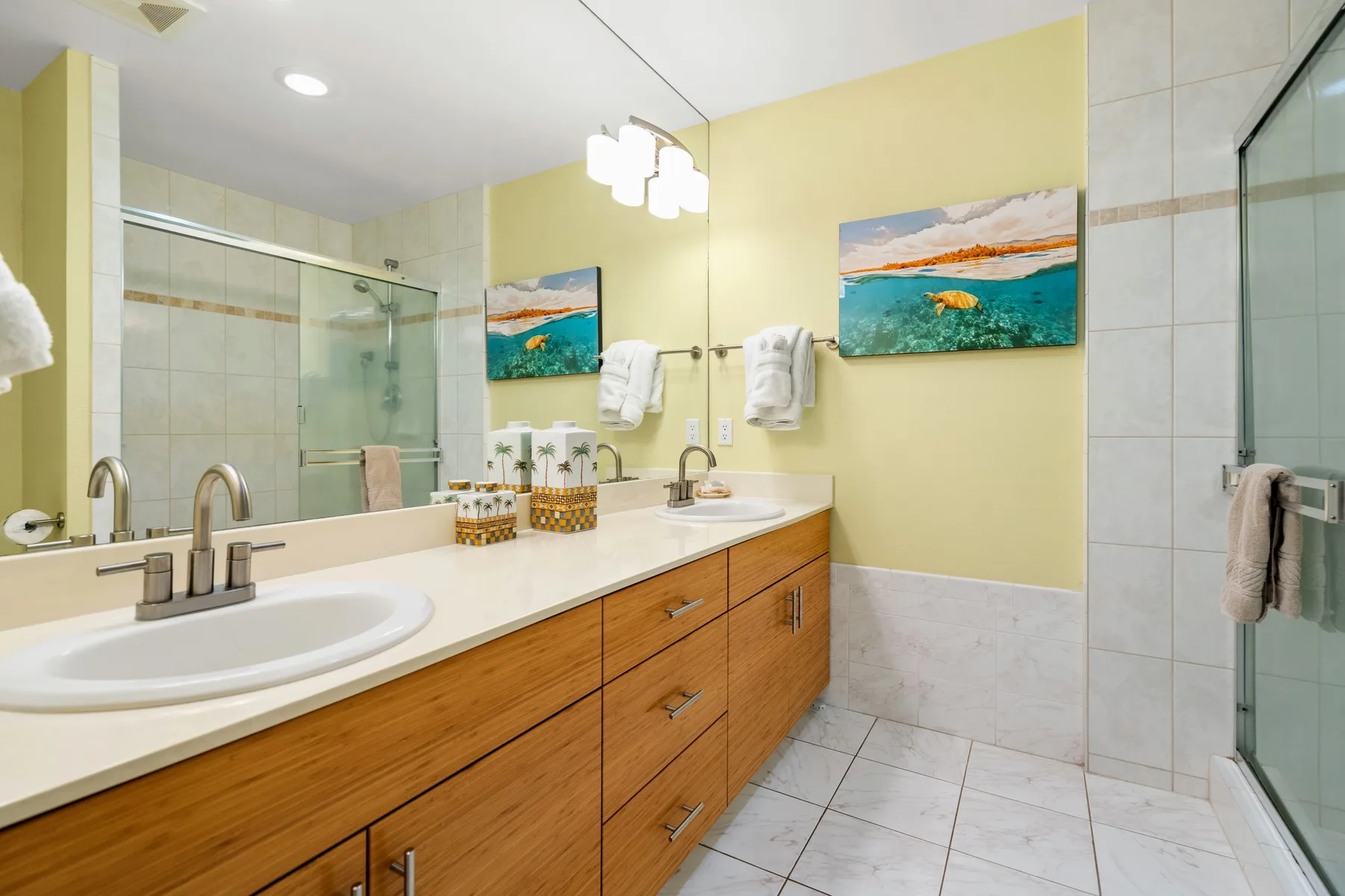Un baño luminoso con un tocador largo, lavabo y ducha de vidrio.