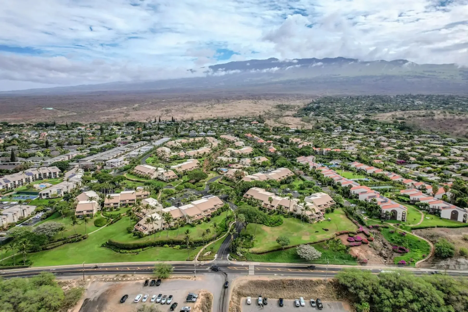 Vista aérea de un barrio residencial con césped verde y montañas a lo lejos.