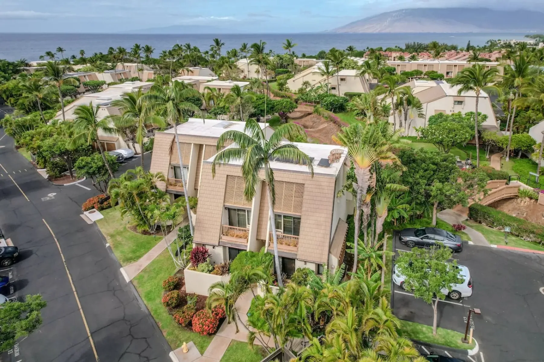 Vista aérea de un complejo residencial tropical con edificios bajos y palmeras.
