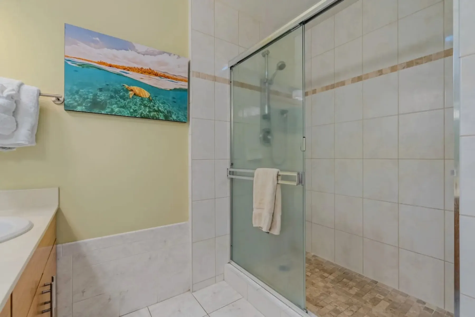 Un baño alicatado con una ducha de vidrio y una toalla colgada en la puerta.