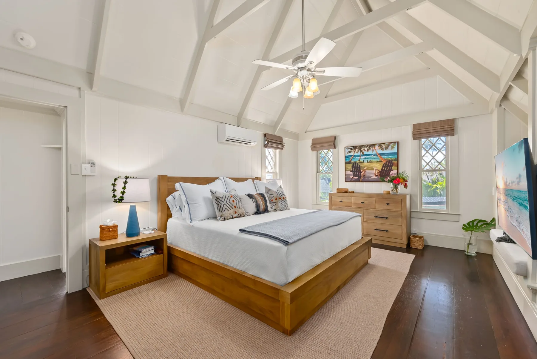 Un dormitorio luminoso con una cama de madera, una mesita y ventanas.