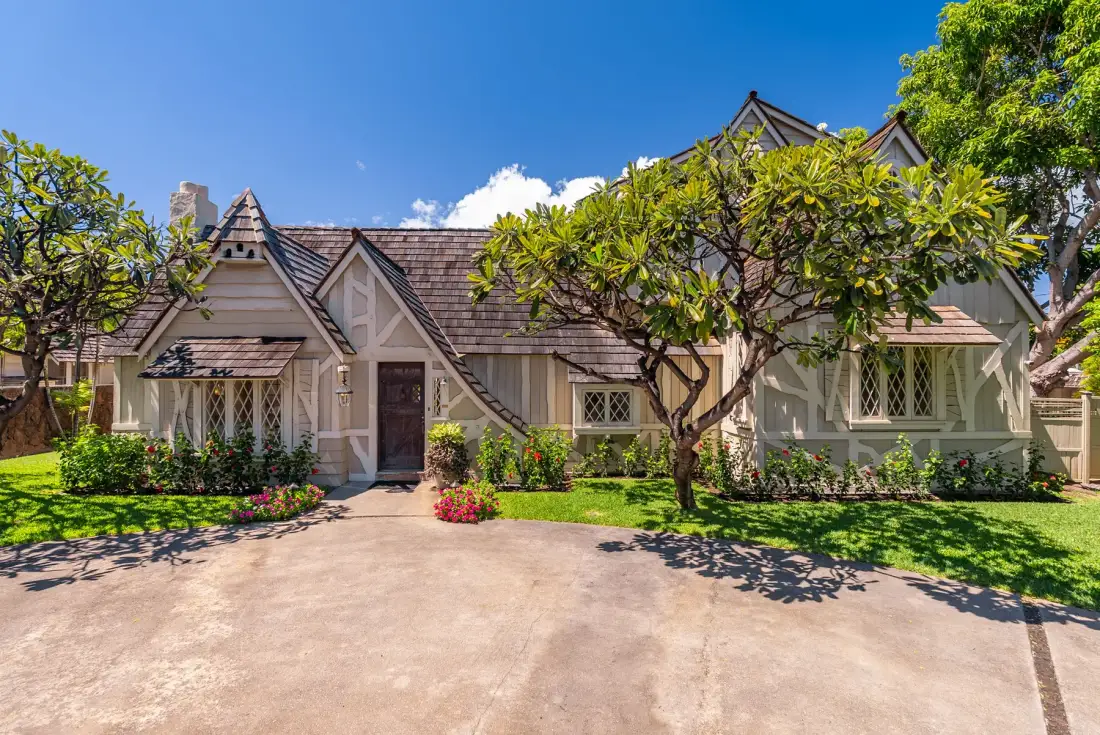 Una casa de estilo cottage con entrada pavimentada y jardín cuidado.