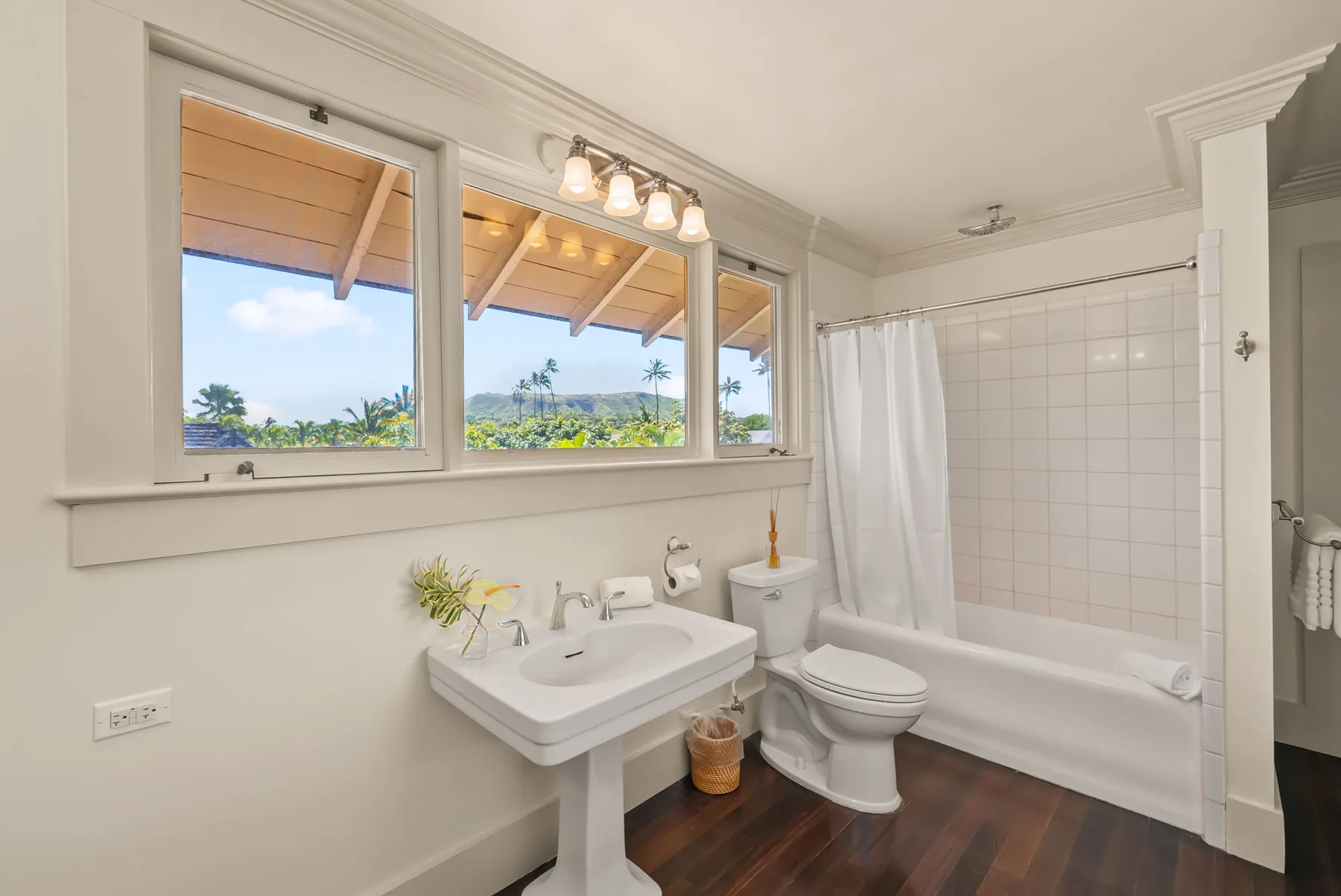 Un baño luminoso con lavabo, inodoro y ventanas con vistas a la vegetación.