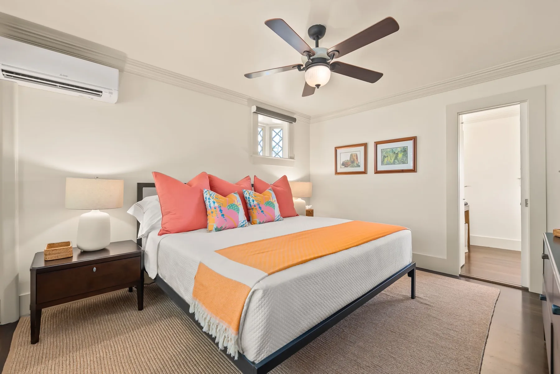 Un dormitorio con una cama vestida con ropa de cama blanca y cojines de colores.