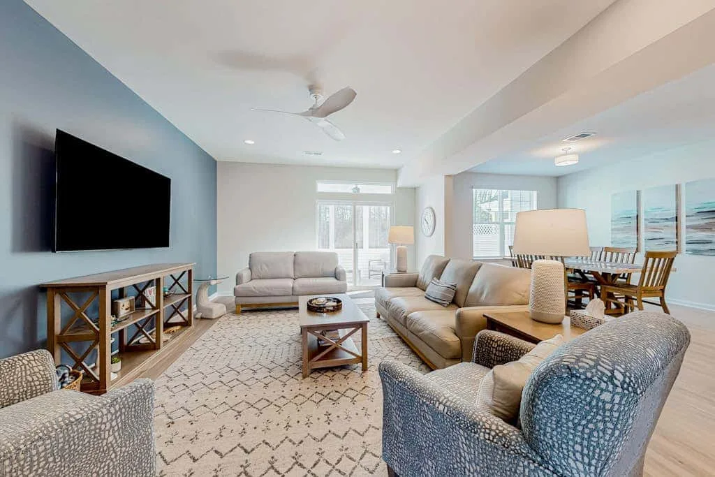 A bright living room with seating, a television, and an open dining area.