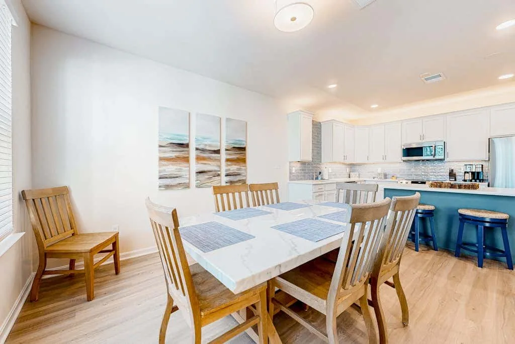Un comedor con mesa y sillas junto a una barra de cocina.
