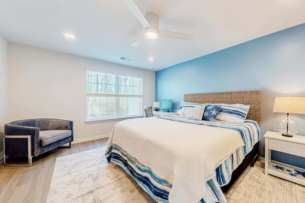 Dormitorio con una cama, una pared azul y una ventana.