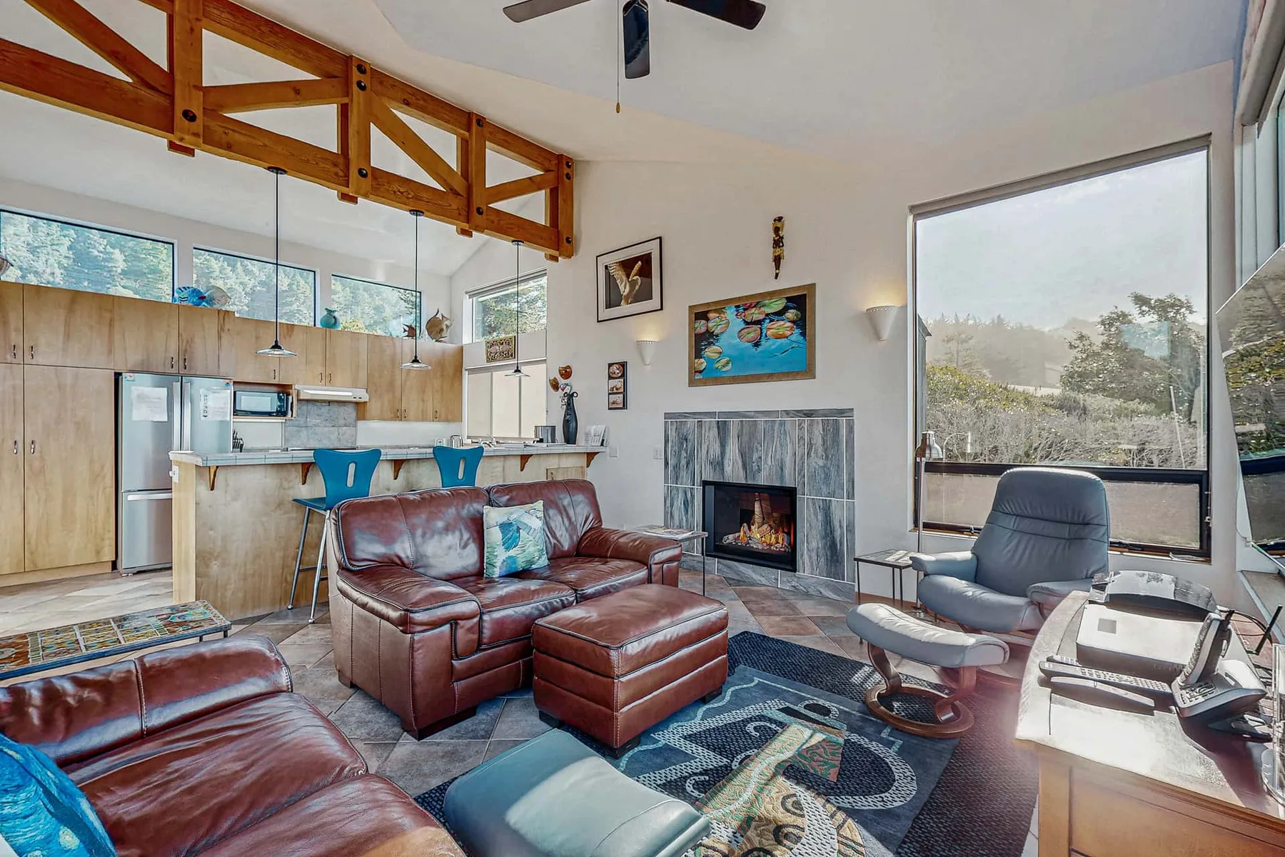 A living room with leather seating, a fireplace, and a large window.