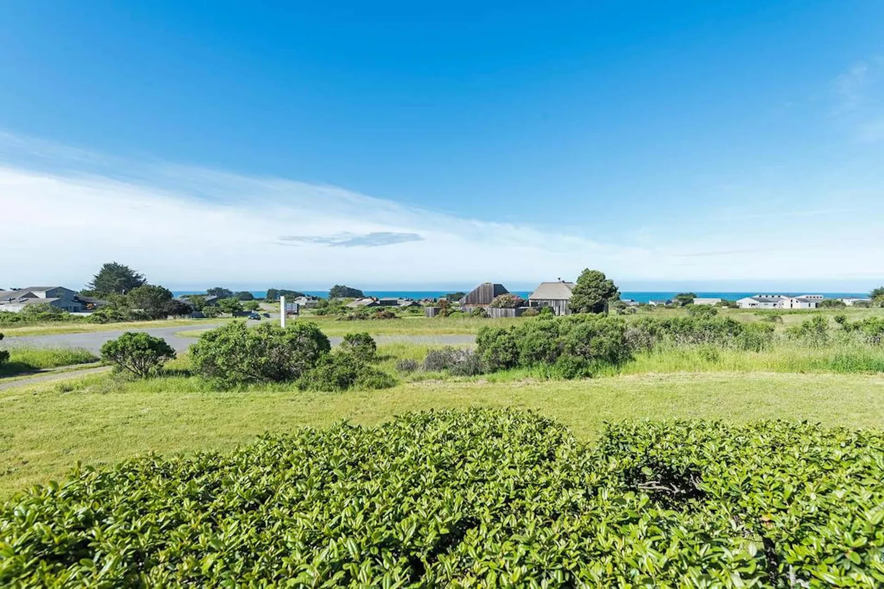 A green coastal landscape with low houses and the ocean visible in the distance.