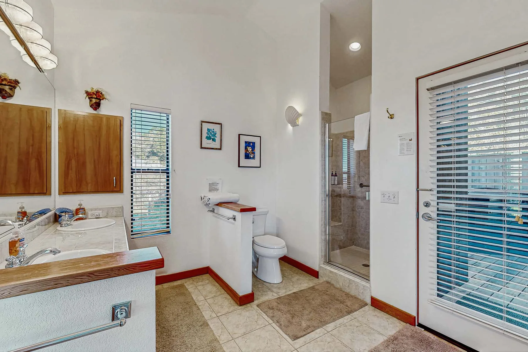 A bright bathroom with a sink, toilet, and glass shower enclosure.