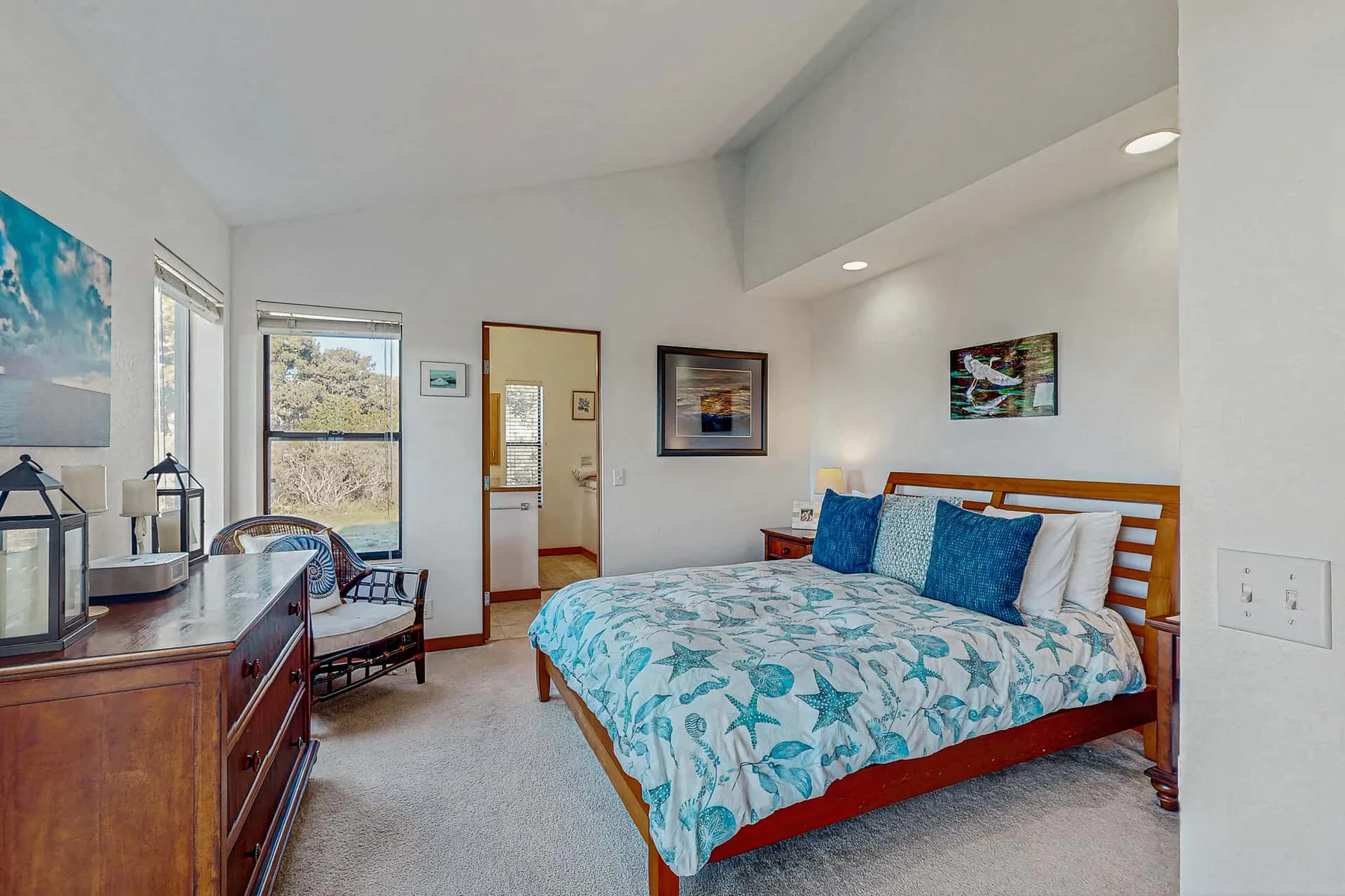 A bedroom with a wooden bed, blue bedding, and a window.
